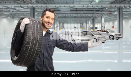 Automechaniker mit einer Reifengeste willkommen in einer Autogarage Stockfoto