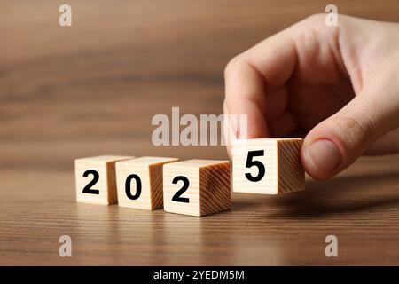 Neujahr 2025. Frau, die Holzwürfel mit Nummer 5 auf den Tisch legt, Nahaufnahme Stockfoto