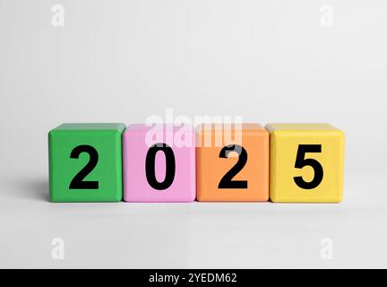 Neujahr 2025, bunte Holzwürfel mit Zahlen auf weißem Tisch, Nahaufnahme Stockfoto