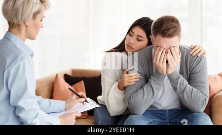 Frau tröstend weinenden Ehemann während Psychotherapie Termin im Psychologen Büro Stockfoto