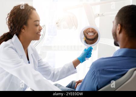 Zahnarzt halten Spiegel für den Patienten zu Zahnweiß-Behandlung Ergebnis zu überprüfen Stockfoto