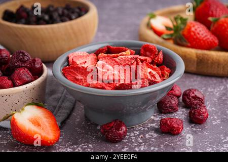 Schüssel mit gefriergetrockneten Erdbeeren und Kirschen auf grauem Hintergrund Stockfoto