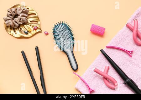 Haarbürste mit Handtuch und Set Friseurwerkzeuge auf orangefarbenem Hintergrund Stockfoto