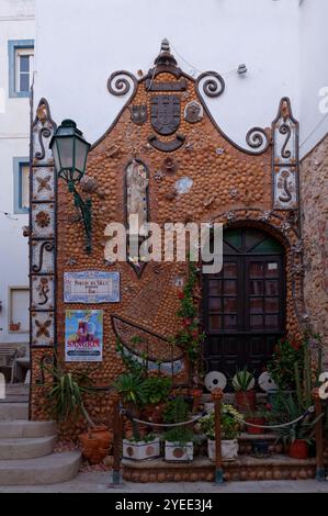 Bezaubernde, mit Muscheln bedeckte Fassade einer lokalen Bar namens Portas da Vila Bar, dekoriert mit Pflanzen und Küstenmotiven Stockfoto