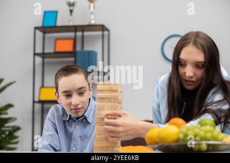 Kinder spielen mit Freude an einem aufregenden Jenga-Spiel mit lebendigen Früchten auf einem Tisch Stockfoto