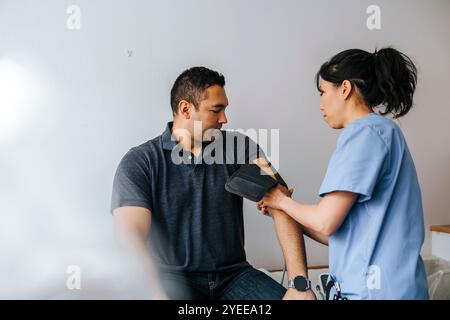 Ärztliche Fachkraft, die den Blutdruck männlicher Patienten im Untersuchungsraum überprüft Stockfoto