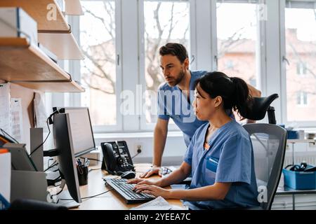 Fokussierte männliche und weibliche medizinische Fachkräfte, die am Computer in der Klinik arbeiten Stockfoto