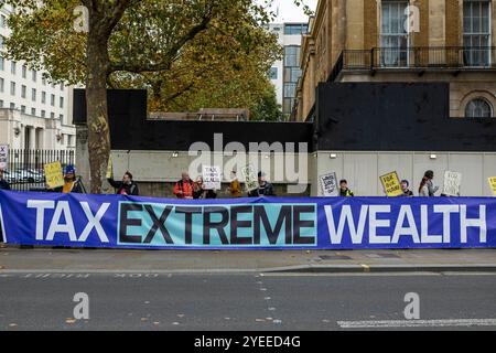 London, Schiedam, Großbritannien. 30. Oktober 2024. Die Demonstranten halten ein Schild mit der Aufschrift „Tax Extreme Rich“. Am 30. Oktober 2024 wurde die Ankündigung des ersten nationalen Haushalts der britischen Labour-Regierung in London auf Proteste gestoßen. Um 11:00 Uhr versammelten sich britische Bürger in der Downing Street 10. Nachdem das Budget gegen 12 Uhr abgelesen worden war, zogen die Demonstranten in die Houses of Parliament im Palace of Westminster. (Kreditbild: © James Petermeier/ZUMA Press Wire) NUR REDAKTIONELLE VERWENDUNG! Nicht für kommerzielle ZWECKE! Stockfoto