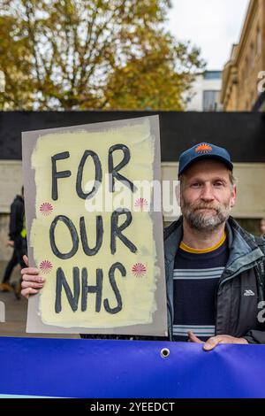 London, Schiedam, Großbritannien. 30. Oktober 2024. Ein Demonstrant hält ein Schild mit der Aufschrift „für unser NHS“. Am 30. Oktober 2024 wurde die Ankündigung des ersten nationalen Haushalts der britischen Labour-Regierung in London auf Proteste gestoßen. Um 11:00 Uhr versammelten sich britische Bürger in der Downing Street 10. Nachdem das Budget gegen 12 Uhr abgelesen worden war, zogen die Demonstranten in die Houses of Parliament im Palace of Westminster. (Kreditbild: © James Petermeier/ZUMA Press Wire) NUR REDAKTIONELLE VERWENDUNG! Nicht für kommerzielle ZWECKE! Stockfoto