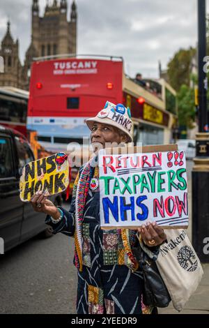 London, Schiedam, Großbritannien. 30. Oktober 2024. Ein Demonstrant hält Schilder, die für das NHS eintreten. Am 30. Oktober 2024 protestierten Mitglieder der britischen Interessenvertretungsgruppe WASPI (Women Against State Pension Injustice) vor den Houses of Parliament. Sie forderten eine Entschädigung für Frauen, die von den Änderungen der Rentengesetze in den Jahren 1995 und 2011 betroffen waren. (Kreditbild: © James Petermeier/ZUMA Press Wire) NUR REDAKTIONELLE VERWENDUNG! Nicht für kommerzielle ZWECKE! Stockfoto