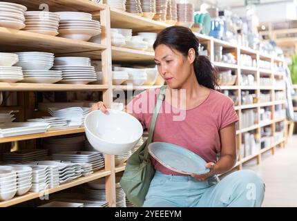 Positive weibliche Käufer wählt neue Teller im Geschirrladen Stockfoto