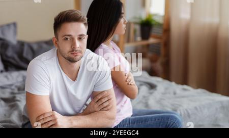 Beleidigtes Paar, Das Zu Hause Auf Verschiedenen Seiten Von Bed At Home Sitzt Stockfoto