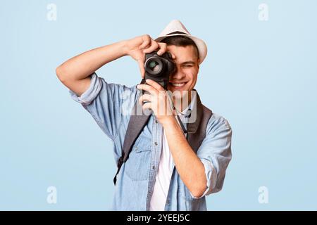 Begeisterte Reisende, die Fotos mit der Kamera über orangefarbenem Hintergrund machen Stockfoto