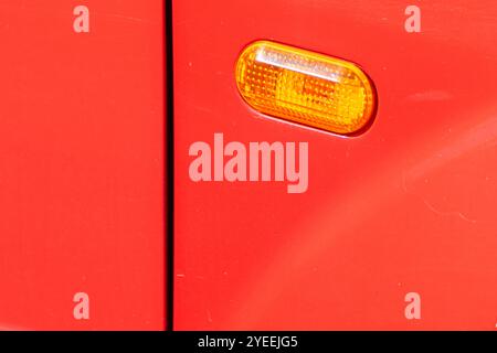 Nahaufnahme des vorderen Seitenblinkers eines roten Autos. Scheinwerfer auf der Fahrerseite in einem Auto Stockfoto