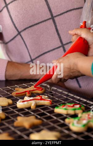 weihnachtskekse mit Glasur dekorieren, ältere Freundinnen backen glücklich zusammen, zu Hause Stockfoto