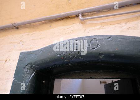 SKEOG graviert oder geschnitzt über dem Eingang und der Tür zu einer Zelle in der Haupthalle des Kilmainham Gaol Gefängnismuseums in Dublin, Irland; Gefangenengraffiti. Stockfoto