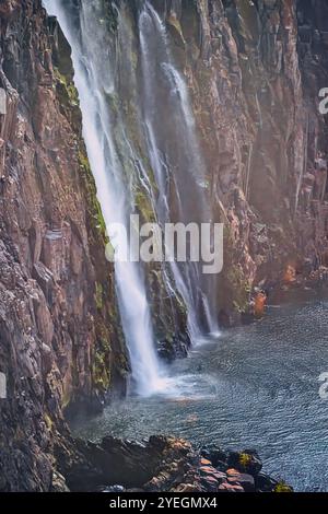 Der mächtige Wasserfall stürzt in einen ruhigen Pool und schafft ein harmonisches Gleichgewicht zwischen dem intensiven Wasserfluss und der friedlichen Umgebung in Sambia Stockfoto