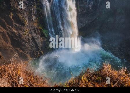 Ein gewaltiger Wasserfall stürzt in einen nebeligen Pool, der ein schaumiges Spray aufwirbelt und natürliche Kraft und unbändige Energie in Simbabwe und Sambia verkörpert Stockfoto