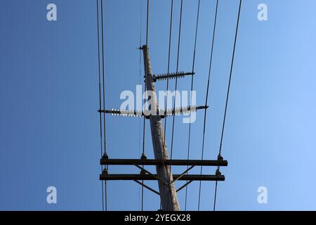 Elektrische Stromleitungen auf Holzturm zur Leitung von Hochspannungsstrom mit blauem Himmel über dem Dach Stockfoto