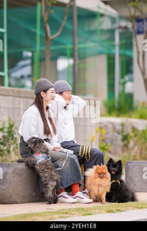 Ein koreanischer Mann und eine Japanerin, beide im Alter von 30 Jahren, laufen mit drei Hunden am Fluss in Pyeongnae-dong, Namyangju-si, Gyeonggi-do, Korea. Stockfoto