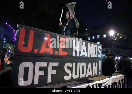 Ein Demonstrant mit einem Megaphon und einem Schild steht hinter einem Banner, auf dem während der Demonstration „VAE Hands Off Sudan“ steht. Demonstranten versammeln sich gegenüber der Downing Street, um gegen die Mittäterschaft der Emirate am Völkermord im Sudan zu demonstrieren. Sie fordern das Ende des Leidens und dass die VAE, die die Rapid Support Forces (RSF) finanzieren und unterstützen, das Land verlassen. Die Organisation Action for Sudan steht für Menschenrechte, Gerechtigkeit und Selbstbestimmung des sudanesischen Volkes. Demonstranten versammelten sich gegenüber der Downing Street, um sich gegen die angebliche Unterstützung der Rapid Support for durch die VAE zu wehren Stockfoto