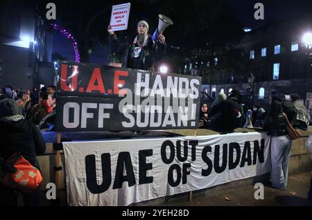 Ein Demonstrant, der ein Megaphon und ein Schild hält, steht hinter Spruchbändern, auf denen während der Demonstration "VAE Hands Off Sudan" und "VAE OUT OF SUDAN" stand. Demonstranten versammeln sich gegenüber der Downing Street, um gegen die Mittäterschaft der Emirate am Völkermord im Sudan zu demonstrieren. Sie fordern das Ende des Leidens und dass die VAE, die die Rapid Support Forces (RSF) finanzieren und unterstützen, das Land verlassen. Die Organisation Action for Sudan steht für Menschenrechte, Gerechtigkeit und Selbstbestimmung des sudanesischen Volkes. Demonstranten versammelten sich gegenüber der Downing Street, um sich gegen die angebliche Unterstützung der VAE zu wehren Stockfoto