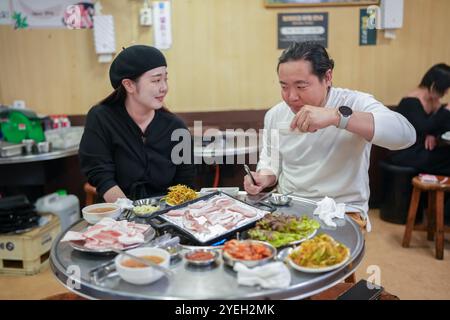 Ein koreanischer Mann und eine Japanerin, beide in ihren 30ern und ein verheiratetes Paar, genießen eine Mahlzeit Samgyeopsal in einem berühmten Restaurant im Bezirk Jung. Stockfoto