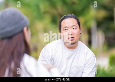 Ein koreanischer Mann und eine Japanerin, beide im Alter von 30 Jahren und ein verheiratetes Paar, genießen in einem stilvollen Café im Herbst einen Brunch mit drei Hunden Stockfoto