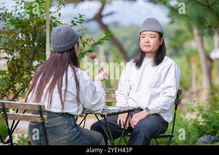 Ein koreanischer Mann und eine Japanerin, beide im Alter von 30 Jahren und ein verheiratetes Paar, genießen in einem stilvollen Café im Herbst einen Brunch mit drei Hunden Stockfoto