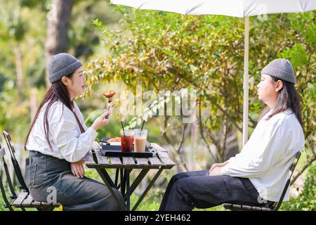 Ein koreanischer Mann und eine Japanerin, beide im Alter von 30 Jahren und ein verheiratetes Paar, genießen in einem stilvollen Café im Herbst einen Brunch mit drei Hunden Stockfoto