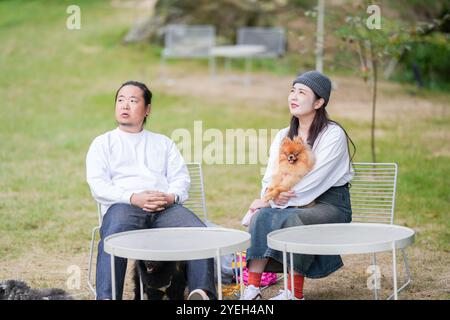 Ein koreanischer Mann und eine Japanerin, beide im Alter von 30 Jahren und ein verheiratetes Paar, genießen in einem stilvollen Café im Herbst einen Brunch mit drei Hunden Stockfoto