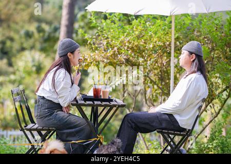 Ein koreanischer Mann und eine Japanerin, beide im Alter von 30 Jahren und ein verheiratetes Paar, genießen in einem stilvollen Café im Herbst einen Brunch mit drei Hunden Stockfoto