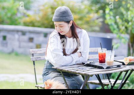 Ein koreanischer Mann und eine Japanerin, beide im Alter von 30 Jahren und ein verheiratetes Paar, genießen in einem stilvollen Café im Herbst einen Brunch mit drei Hunden Stockfoto
