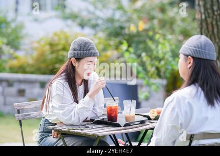 Ein koreanischer Mann und eine Japanerin, beide im Alter von 30 Jahren und ein verheiratetes Paar, genießen in einem stilvollen Café im Herbst einen Brunch mit drei Hunden Stockfoto