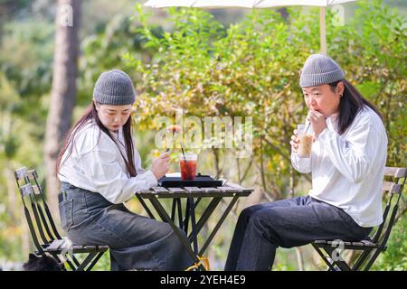 Ein koreanischer Mann und eine Japanerin, beide im Alter von 30 Jahren und ein verheiratetes Paar, genießen in einem stilvollen Café im Herbst einen Brunch mit drei Hunden Stockfoto