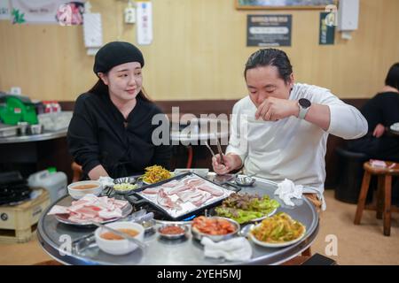 Ein koreanischer Mann und eine Japanerin, beide in ihren 30ern und ein verheiratetes Paar, genießen eine Mahlzeit Samgyeopsal in einem berühmten Restaurant im Bezirk Jung. Stockfoto
