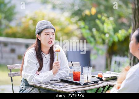 Ein koreanischer Mann und eine Japanerin, beide im Alter von 30 Jahren und ein verheiratetes Paar, genießen in einem stilvollen Café im Herbst einen Brunch mit drei Hunden Stockfoto