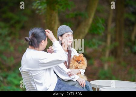 Ein koreanischer Mann und eine Japanerin, beide im Alter von 30 Jahren und ein verheiratetes Paar, genießen in einem stilvollen Café im Herbst einen Brunch mit drei Hunden Stockfoto