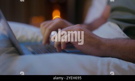 Nahaufnahme Mann Hände liegen im Bett Tippen Laptop mit Computer-Gadget Online-Technologie Nachtarbeit Freiberufliches Internet Web-Surfen SMS-Chats Stockfoto