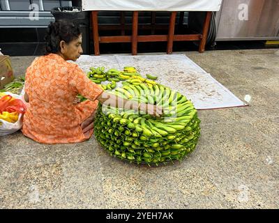 Im Inneren des Hindutempels stapelt indianerin die Bananen in kreisförmiger Form, um sie den Göttern darzubringen. Sri Thendayuthapani Tempel. Singapur. Stockfoto