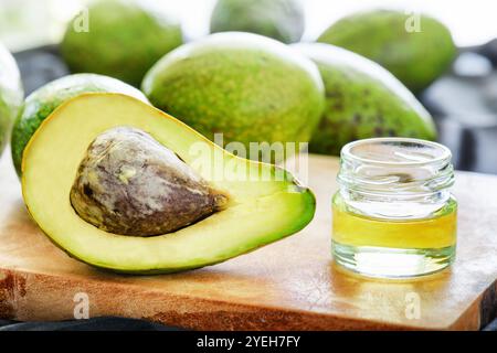 Frische reife Avocado und natürliches Avocadoöl auf Holzbrett Stockfoto