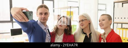 Ein Mann macht Selfie auf einem Smartphone mit Kollegen im Büro Stockfoto