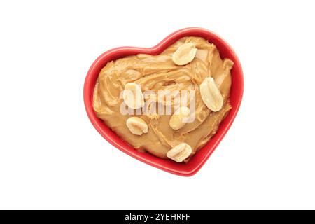 Herzförmige Schüssel mit Erdnussbutter und Erdnüssen isoliert auf weißem Hintergrund. Draufsicht Stockfoto