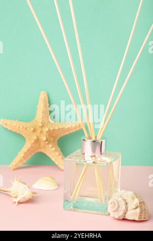 Reed-Diffusor und Muscheln auf mintfarbenem Hintergrund. Vertikales Foto. Draufsicht Stockfoto