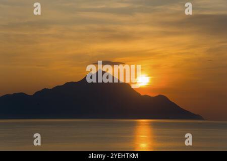 Sonnenaufgang hinter einem Berg mit goldenen Reflexen auf dem Meer, Blick auf den Berg Athos, orthodoxe mönchsrepublik mit autonomem Status unter griechischem Sover Stockfoto