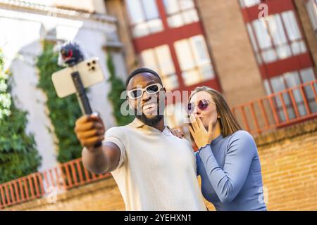 Multi-ethnische Paare verwenden Handheld-Gimbal für Vlogging im Freien Stockfoto