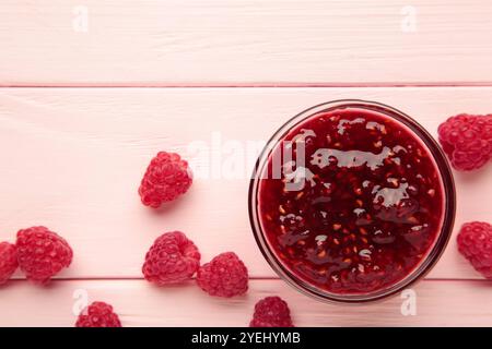 Himbeermarmelgelee in Schüssel mit Beeren auf rosa Hintergrund. Draufsicht Stockfoto