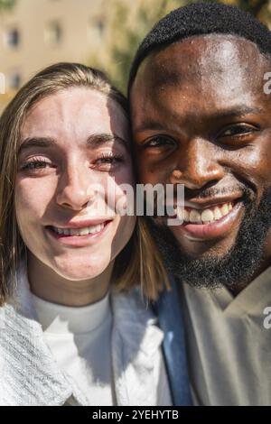 Vertikales Nahporträt eines lächelnden multirassischen jungen Paares draußen Stockfoto