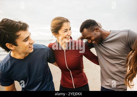 Drei Freunde A, die am frühen Morgen am Strand laufen. Ihre entspannte Haltung und das aufrichtige Lächeln heben die Themen Freundschaft, Freizeit und hervor Stockfoto