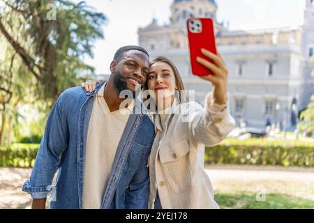 Frontalansicht eines glücklichen, multiethnischen Paares, das Selfie im Stadtblick macht Stockfoto